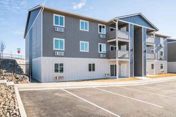 A blue and white apartment building with a parking lot